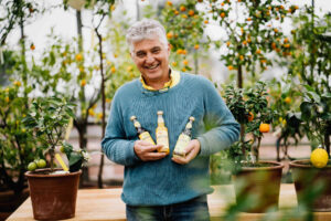 Zitrusbauer Michael Ceron in seinem Zitrusgarten mit einer Auswahl von Slowfood-Zitrusgetränken